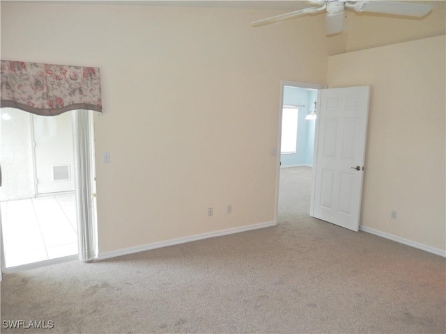 carpeted spare room featuring ceiling fan and a towering ceiling