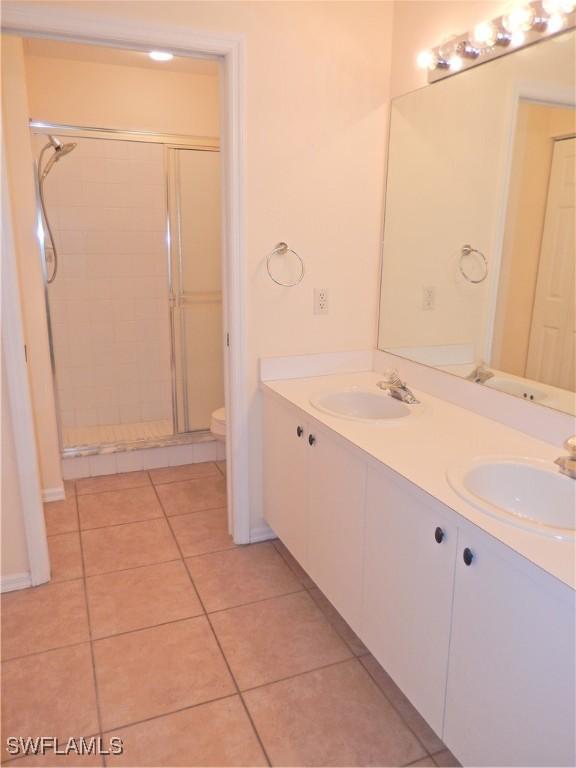 bathroom featuring toilet, a shower with door, vanity, and tile patterned floors