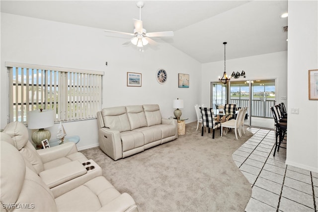 carpeted living room with high vaulted ceiling and ceiling fan with notable chandelier