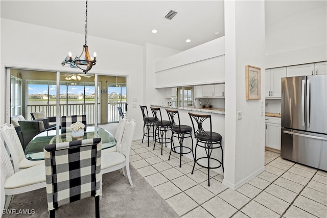 dining room with an inviting chandelier, light tile patterned floors, and a high ceiling