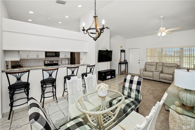 carpeted dining room with vaulted ceiling, sink, and ceiling fan with notable chandelier