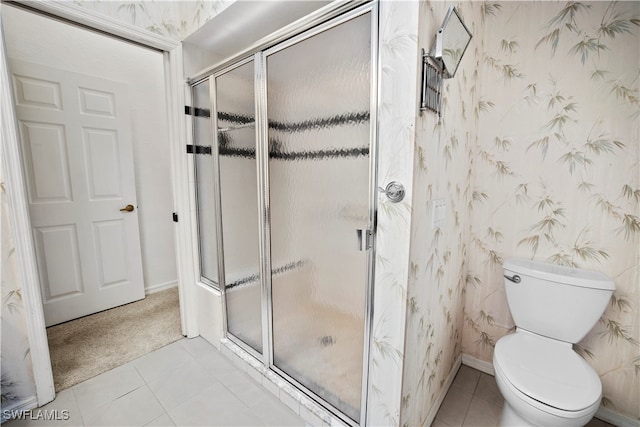 bathroom featuring tile patterned floors, toilet, and a shower with shower door