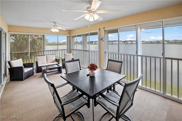 sunroom / solarium featuring a water view and ceiling fan