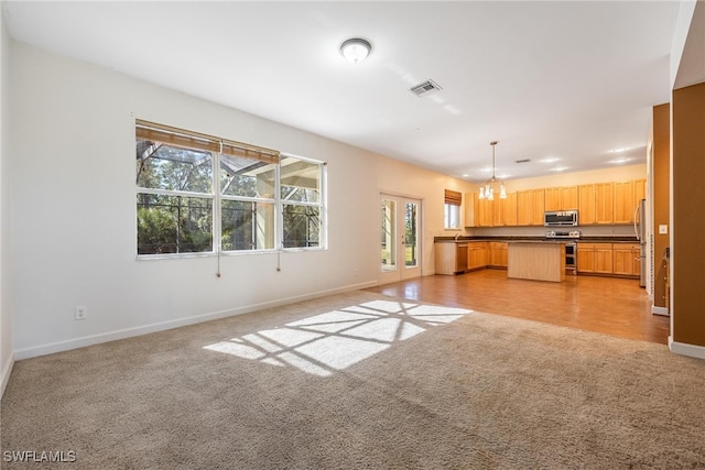 unfurnished living room with light colored carpet and an inviting chandelier