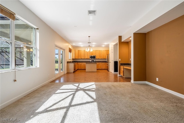 kitchen featuring a center island, a chandelier, decorative light fixtures, light carpet, and appliances with stainless steel finishes