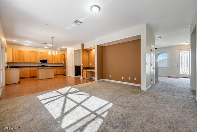 unfurnished living room featuring light wood-type flooring, a notable chandelier, and sink