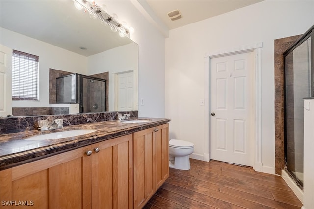 bathroom featuring hardwood / wood-style floors, vanity, toilet, and walk in shower