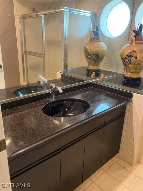 bathroom featuring tile patterned floors, a shower with shower door, and vanity