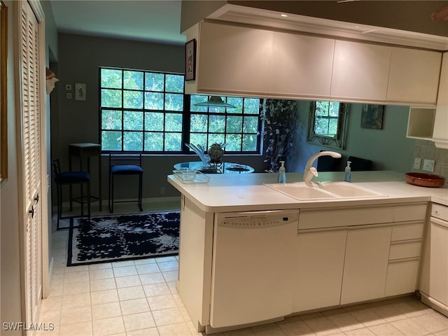 kitchen featuring white cabinets, light tile patterned floors, dishwasher, sink, and kitchen peninsula