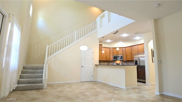 kitchen with hanging light fixtures, light tile patterned floors, backsplash, stainless steel appliances, and kitchen peninsula