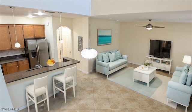 kitchen featuring hanging light fixtures, vaulted ceiling, stainless steel fridge, ceiling fan, and a kitchen bar