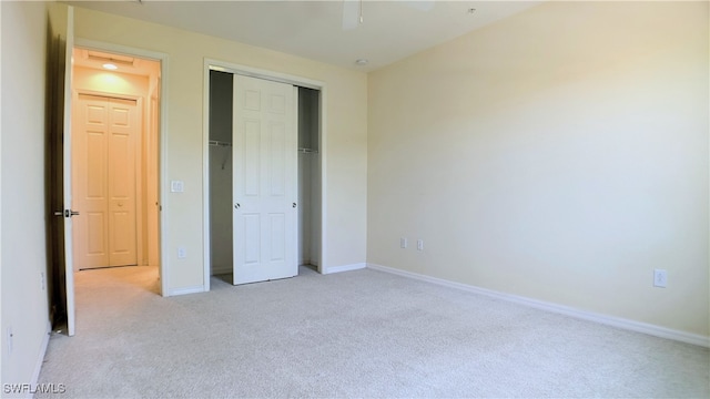 unfurnished bedroom featuring light carpet, ceiling fan, and a closet