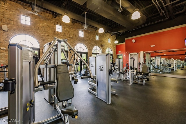 workout area with brick wall and a towering ceiling