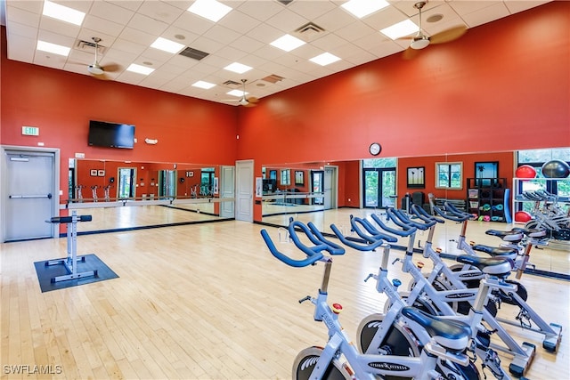 gym featuring a paneled ceiling, a high ceiling, and light hardwood / wood-style floors