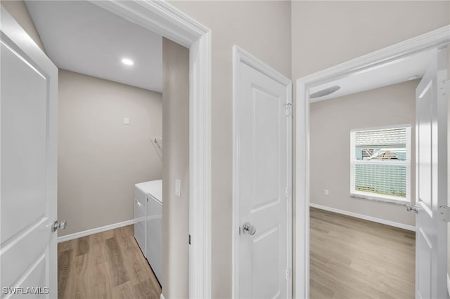 clothes washing area with separate washer and dryer and light hardwood / wood-style floors