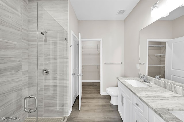 bathroom featuring a shower with shower door, hardwood / wood-style flooring, vanity, and toilet