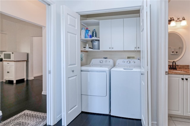 washroom featuring cabinets, dark tile patterned floors, sink, and washing machine and dryer