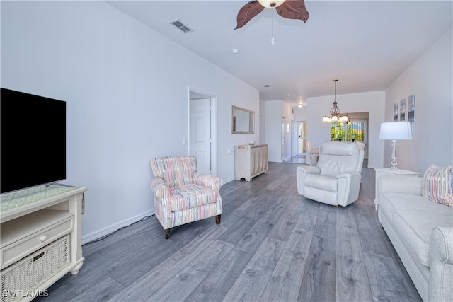 living room featuring ceiling fan with notable chandelier and dark wood-type flooring