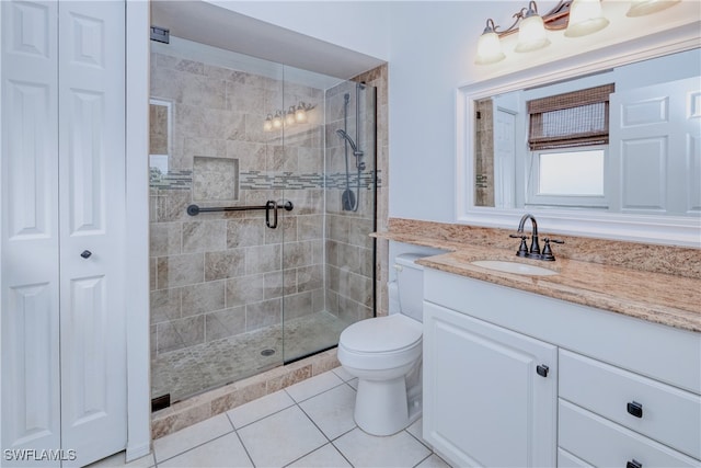 bathroom with tile patterned flooring, a shower with door, vanity, and toilet