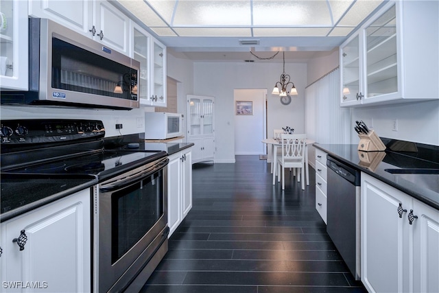 kitchen featuring white cabinets, pendant lighting, dark wood-type flooring, stainless steel appliances, and an inviting chandelier