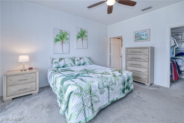 bedroom with light colored carpet, a closet, a walk in closet, and ceiling fan