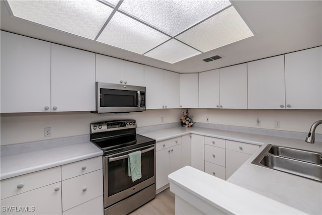 kitchen featuring stainless steel appliances, light countertops, a sink, and visible vents