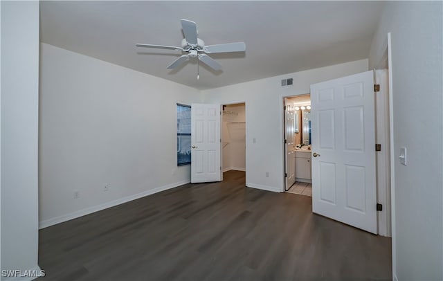 unfurnished bedroom with a walk in closet, a closet, visible vents, wood finished floors, and baseboards