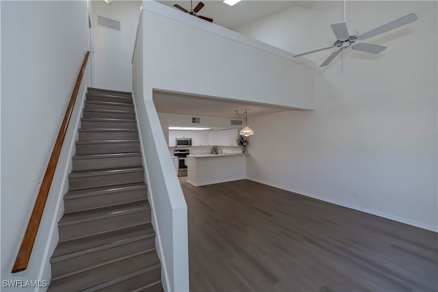 staircase with baseboards, visible vents, a ceiling fan, and wood finished floors