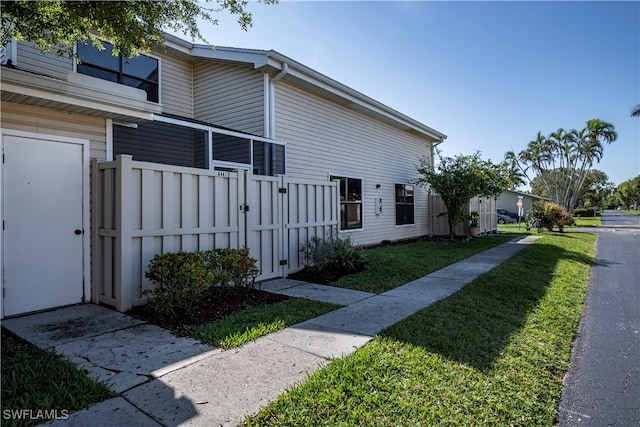 view of property exterior featuring a lawn and fence