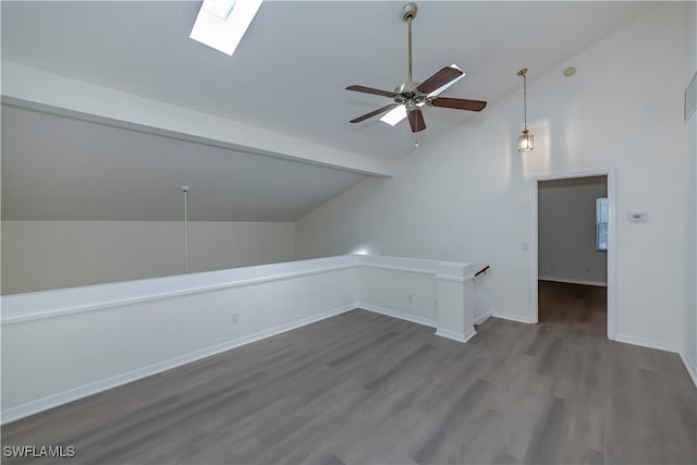 bonus room featuring ceiling fan, vaulted ceiling with skylight, wood finished floors, and baseboards