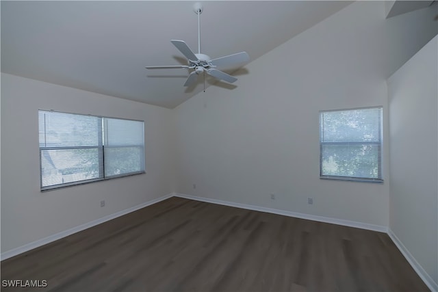 spare room with lofted ceiling, dark wood-type flooring, baseboards, and a healthy amount of sunlight