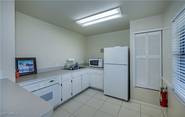 kitchen with light tile patterned floors, white appliances, a sink, white cabinetry, and light countertops