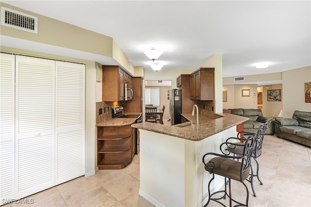 kitchen with sink, appliances with stainless steel finishes, kitchen peninsula, and decorative backsplash