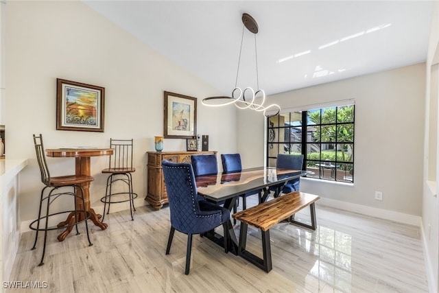 dining area with a notable chandelier, light wood-type flooring, and vaulted ceiling