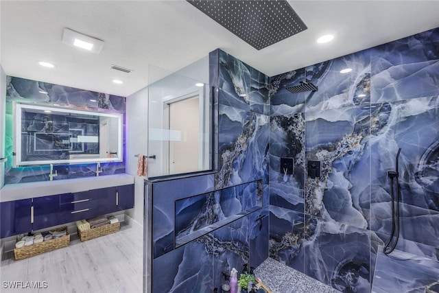 bathroom featuring vanity, hardwood / wood-style flooring, a shower, and tile walls