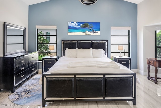 bedroom with light hardwood / wood-style flooring and high vaulted ceiling