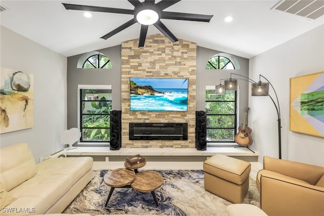 living room with lofted ceiling, ceiling fan, and a stone fireplace