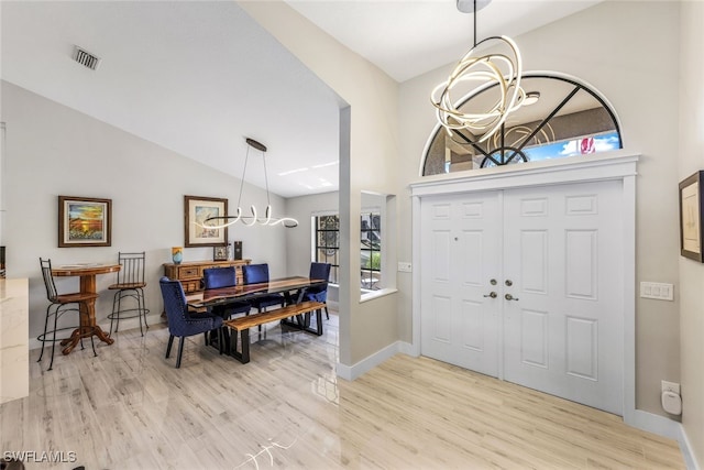 foyer with an inviting chandelier, light hardwood / wood-style flooring, and vaulted ceiling