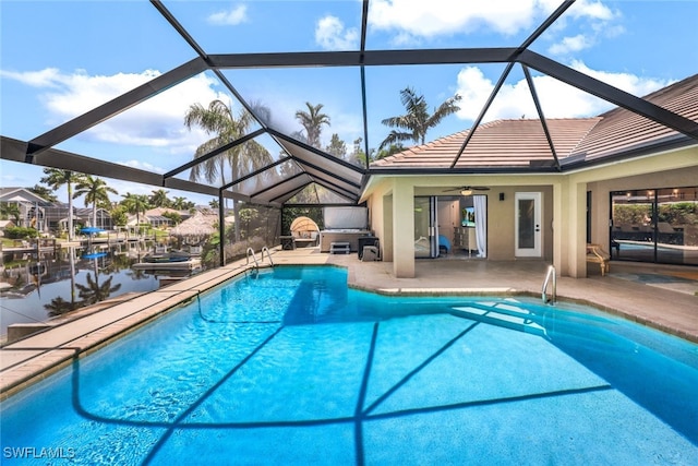 view of swimming pool with glass enclosure, ceiling fan, and a patio area