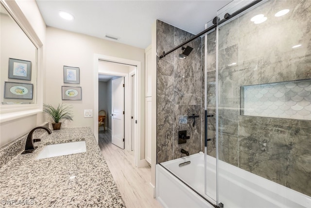 bathroom with wood-type flooring, vanity, and combined bath / shower with glass door