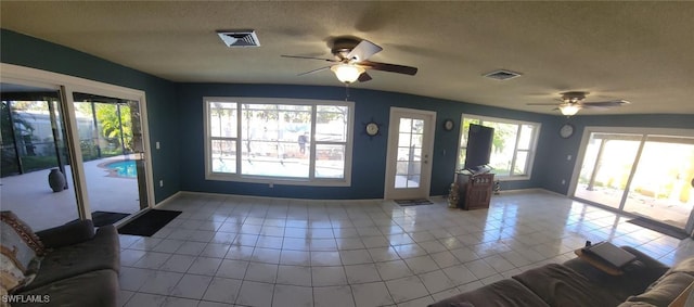 interior space featuring a textured ceiling, ceiling fan, light tile patterned flooring, and plenty of natural light