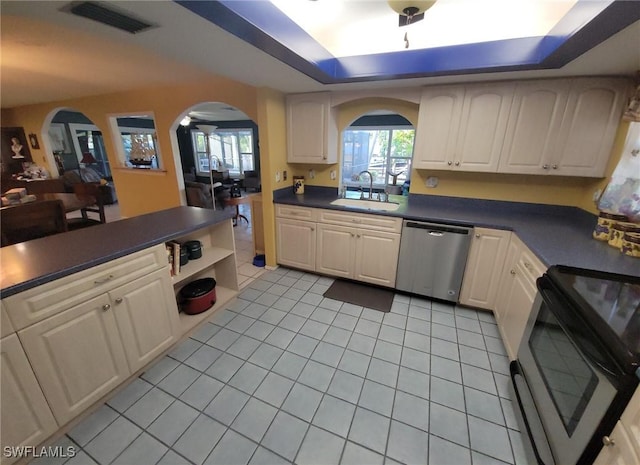 kitchen with black electric range, stainless steel dishwasher, sink, a tray ceiling, and light tile patterned floors