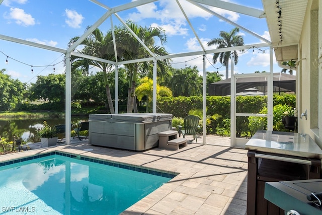 view of swimming pool with a hot tub, glass enclosure, a patio, and a water view