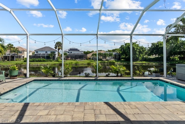 view of pool with glass enclosure, a water view, and a patio area