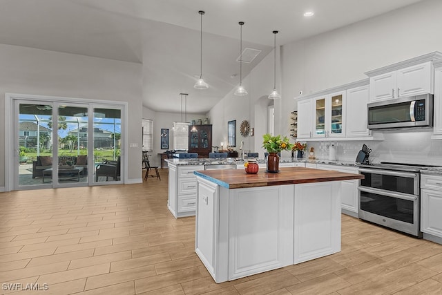 kitchen with a center island, white cabinetry, wood counters, and stainless steel appliances