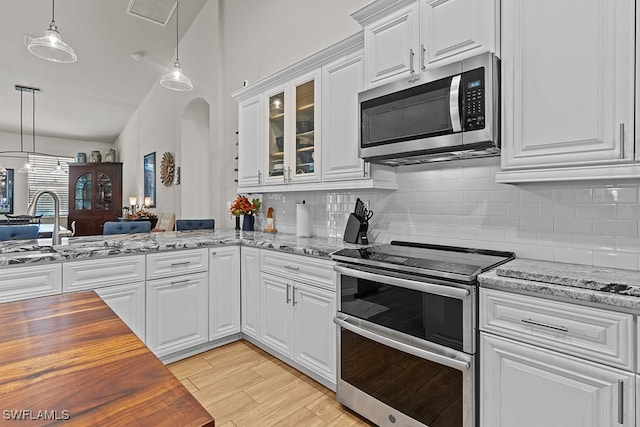 kitchen featuring light stone counters, stainless steel appliances, white cabinets, and light hardwood / wood-style floors