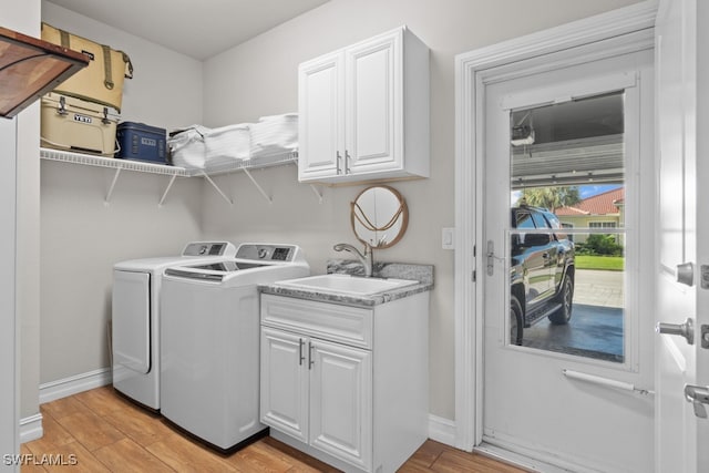 laundry area featuring cabinets, light hardwood / wood-style floors, washing machine and clothes dryer, and sink