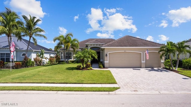 mediterranean / spanish-style house featuring a tiled roof, an attached garage, decorative driveway, a front yard, and stucco siding