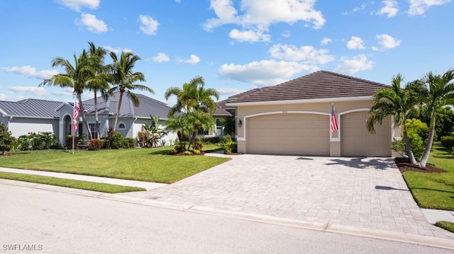 ranch-style home featuring an attached garage, a tiled roof, decorative driveway, stucco siding, and a front lawn