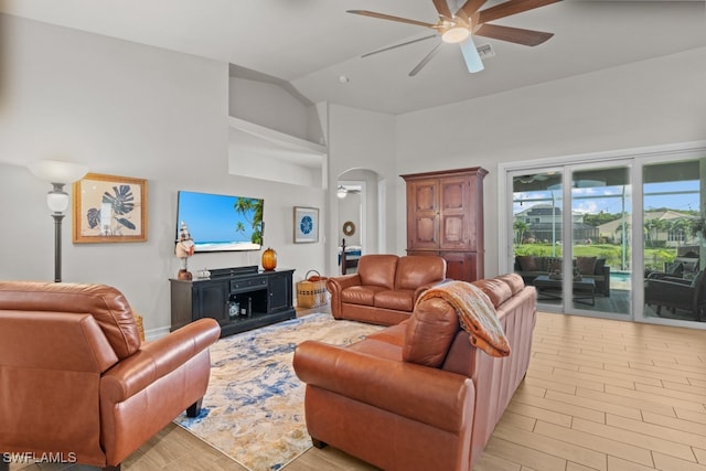 living room with light hardwood / wood-style flooring, ceiling fan, and high vaulted ceiling